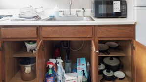 Una cocina con armarios de madera, un microondas y un lavamanos.