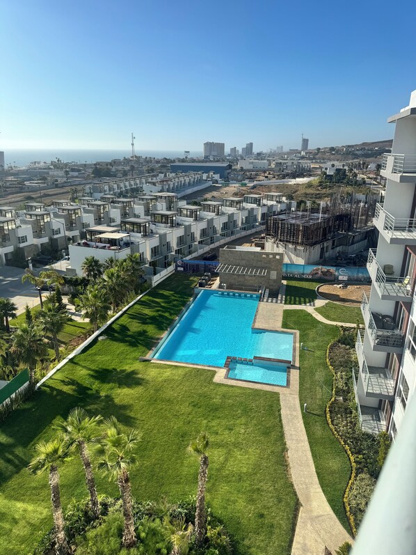 A modern residential area with a swimming pool, well-maintained lawns, and a clear view of the ocean. - 3BR Oceanview Penthouse, AC, Sleep 8, Gated, Pool, Playground, BBQ, Security24-7 (Rosarito)