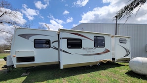A Rockwood Signature ULTRALITE RV parked on grass with a clear sky.
