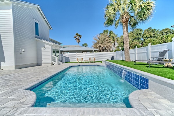 Une piscine dont le bord est revêtu de carrelage, entourée d’une terrasse et d’une clôture blanche.