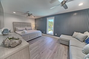A modern bedroom with a large bed, a desk, and a sofa.