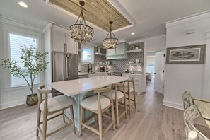 A modern kitchen with a large island, stainless steel appliances, and a wooden ceiling.