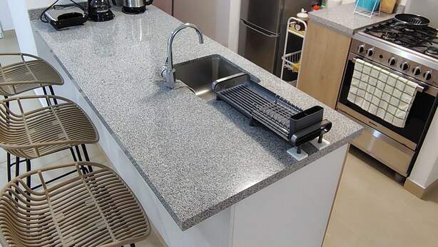 Een moderne keuken met een granieten aanrechtblad, roestvrijstalen apparatuur en een inbouwoven.