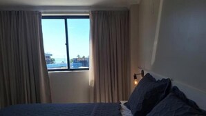 Une chambre d’hôtel avec un grand lit, une fenêtre avec des rideaux et une vue sur les bâtiments environnants.