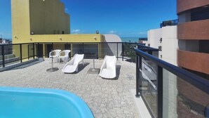 Un espace piscine aménagé sur le toit, avec des chaises longues et un panneau indiquant la présence d’un bar sur le toit.