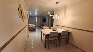 Un vaste espace dédié à la salle à manger, avec une longue table et des chaises, un élément décoratif mural et un éclairage encastré.