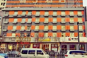 A multi-story building with a row of windows, some with orange blinds, and a storefront with signage. - Orange Hotel (Taiyuan Qinxian North Street Maoye Tiandi Branch) (Taiyuan)