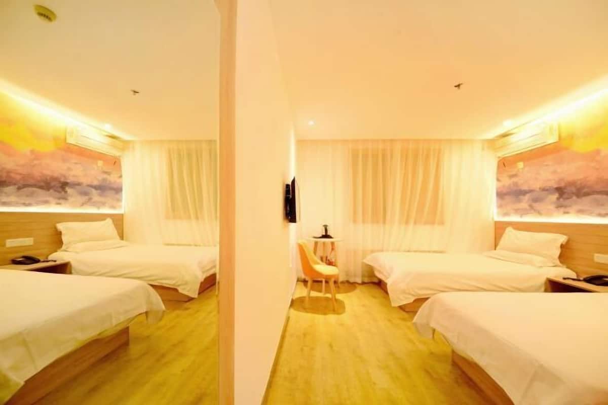 A hotel room with two single beds, a small table, and a chair.