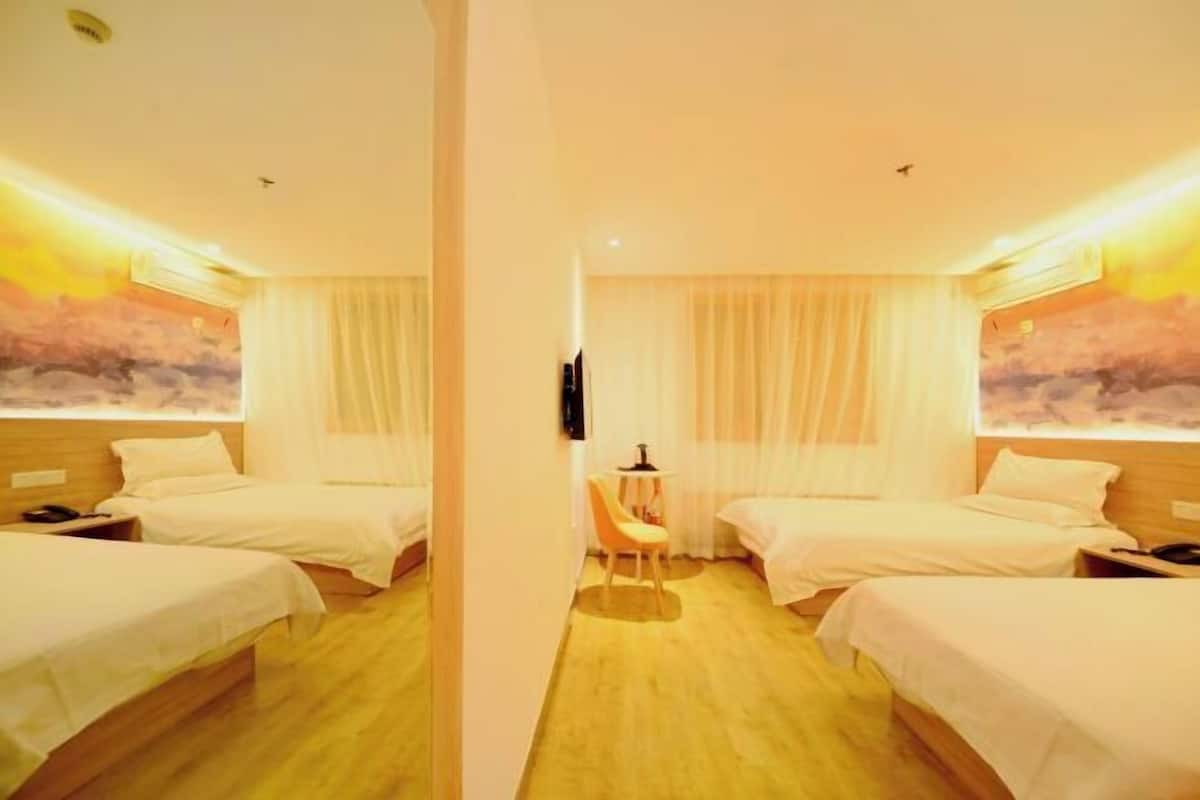 A hotel room with two beds, a small table, and a chair.