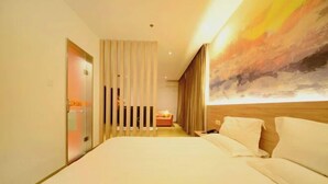 A hotel room with a large bed, a desk, a chair, and a painting on the wall. - Orange Hotel (Taiyuan Qinxian North Street Maoye Tiandi Branch) (Taiyuan)