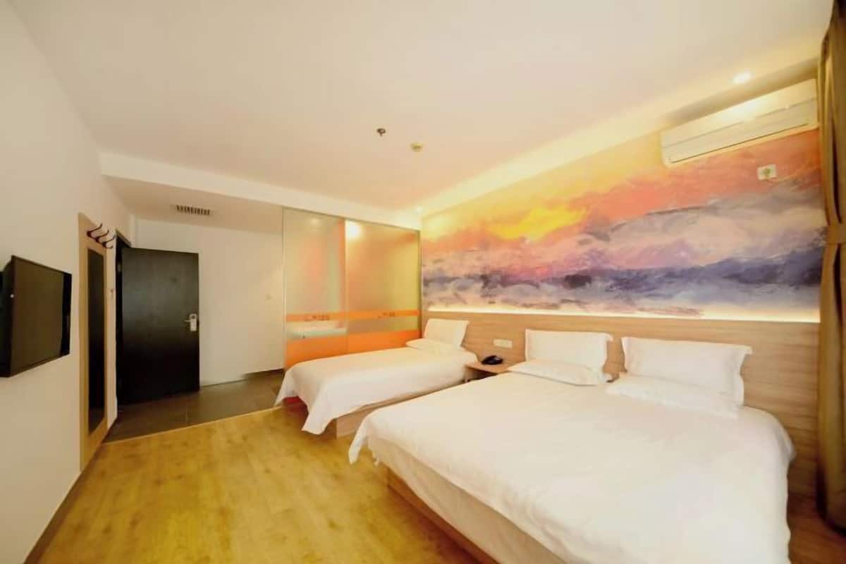 A hotel room with two beds, a large abstract painting on the wall, a wooden floor, and a TV mounted on the wall.