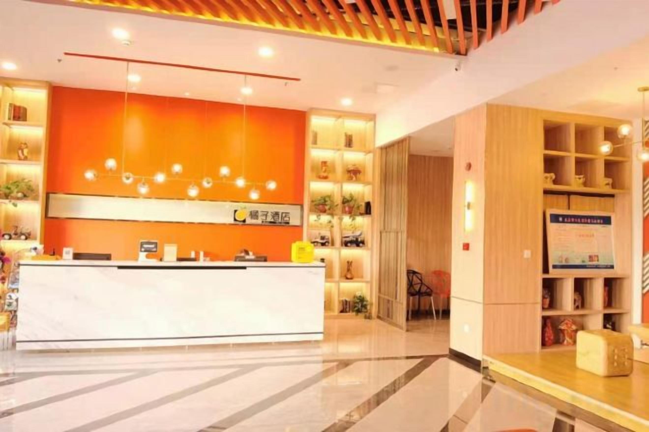 A hotel reception area with a modern design, featuring a reception desk, a wooden panel wall, and a well-lit interior.