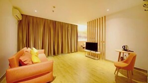 A modern hotel room with a sofa, a TV, a small table, and a chair. - Orange Hotel (Taiyuan Qinxian North Street Maoye Tiandi Branch) (Taiyuan)