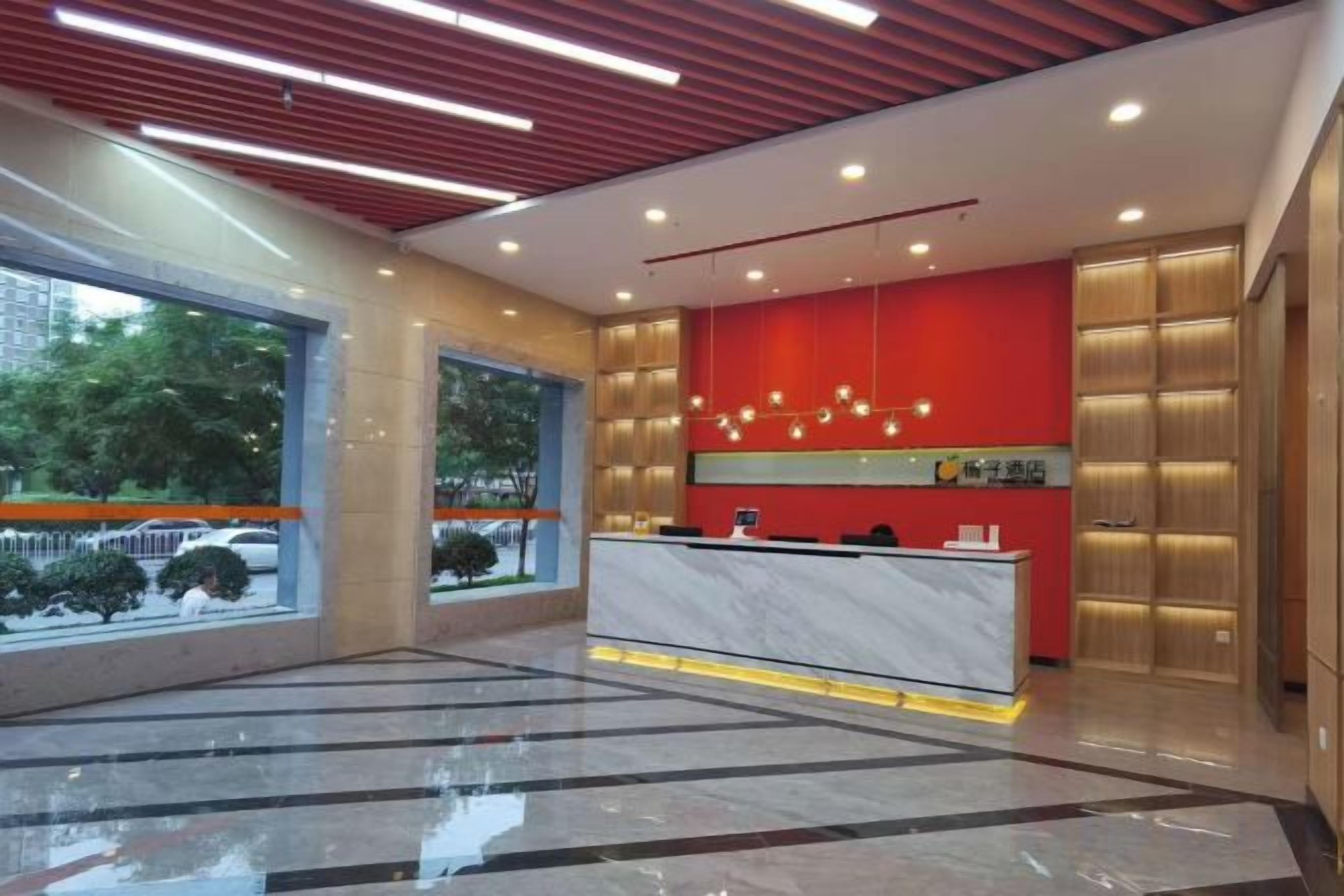 A hotel lobby with a reception desk, large windows, and a red accent wall.