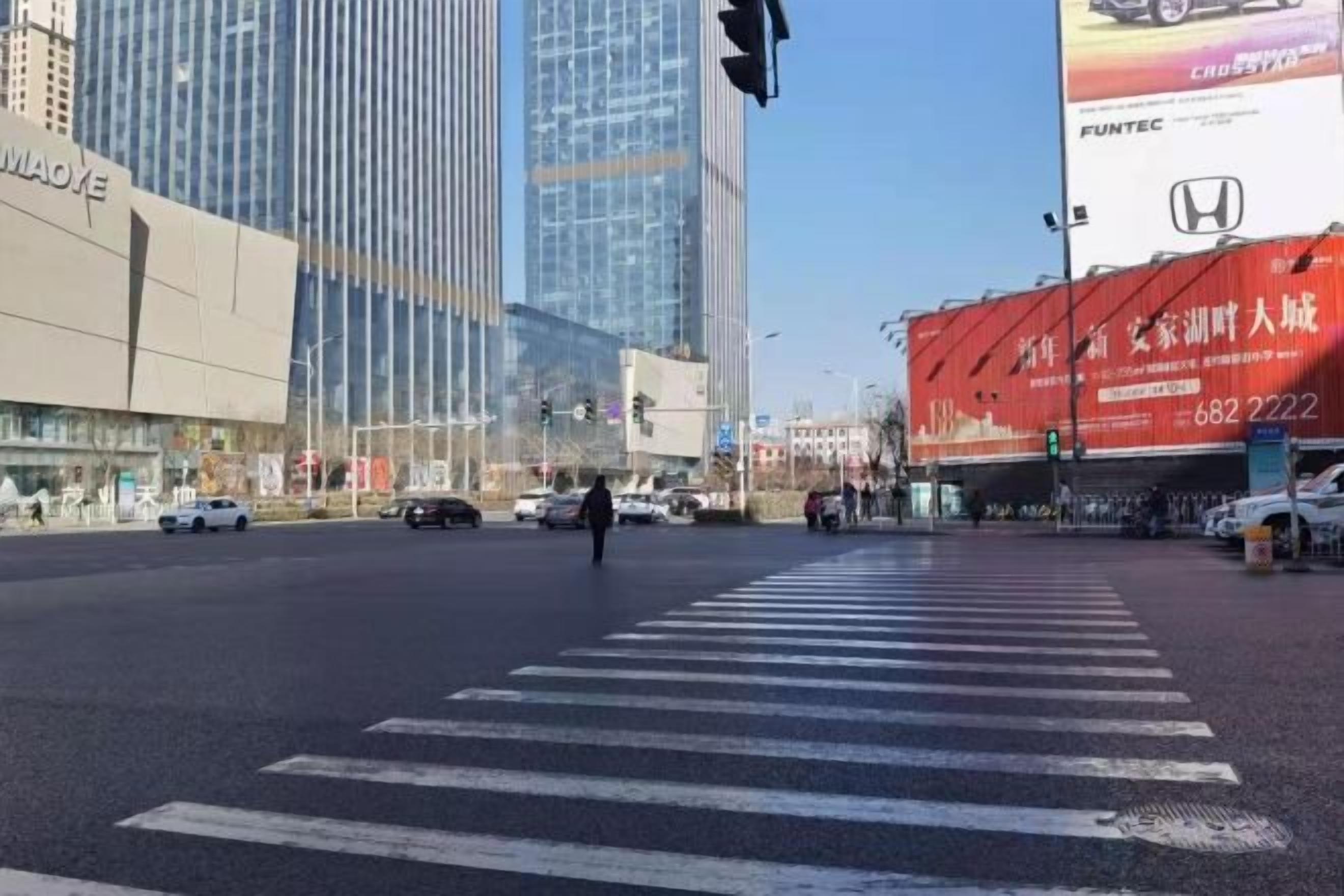 A city intersection with tall buildings, a crosswalk, and traffic lights.