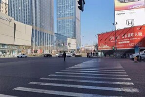 A city intersection with tall buildings, a crosswalk, and traffic lights. - Orange Hotel (Taiyuan Qinxian North Street Maoye Tiandi Branch) (Taiyuan)