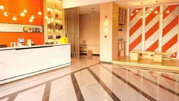 A hotel reception area with a marble floor, a reception desk, and a striped wall design.