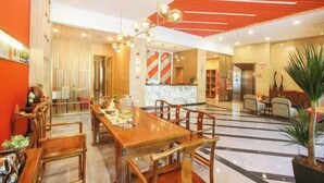 A hotel lobby with a wooden reception desk, a large dining table with chairs, and a modern ceiling design. - Orange Hotel (Taiyuan Qinxian North Street Maoye Tiandi Branch) (Taiyuan)