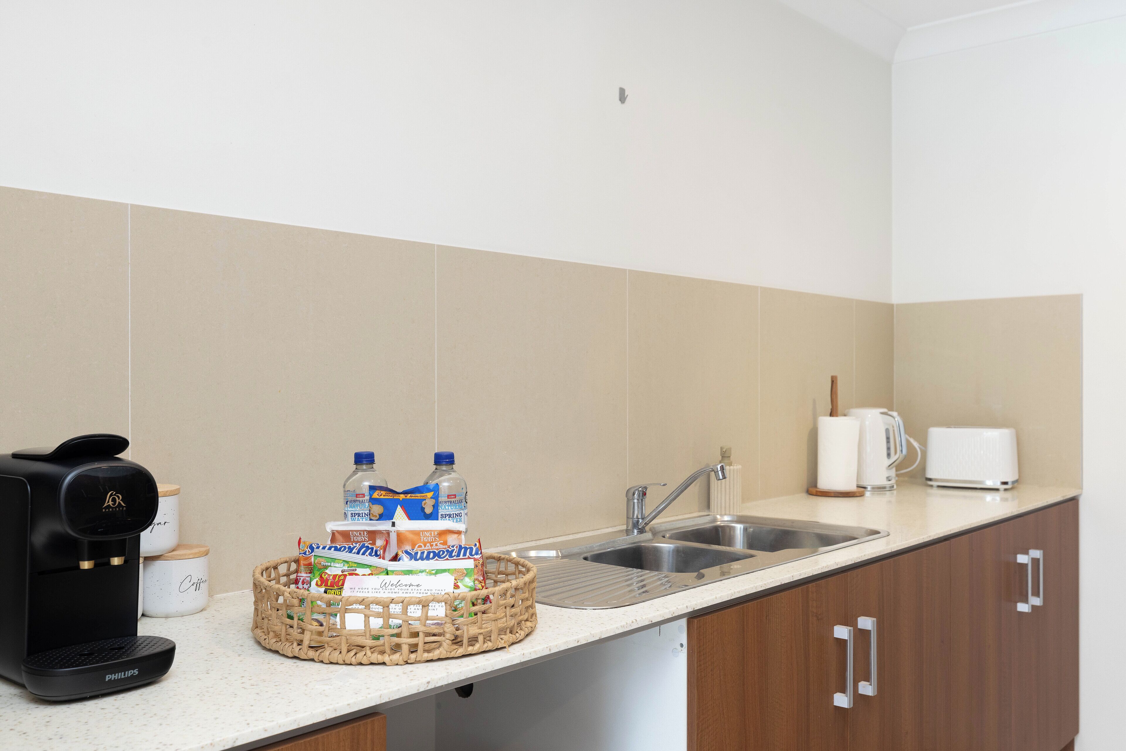 A kitchen with a coffee maker, a basket of milk cartons, a toaster, and a sink.