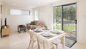 Un salon moderne comprenant un coin repas, un canapé, un téléviseur et un balcon agrémenté d’une rambarde.