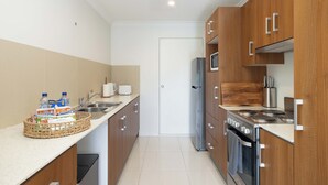 Une cuisine moderne avec des meubles en bois, des appareils en acier inoxydable et un plan de travail blanc.