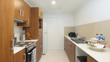 A modern kitchen with wooden cabinets, stainless steel appliances, and a white countertop.