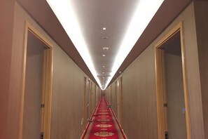 A hotel hallway with wooden walls, a red carpet, and doors on both sides. - Baotai Business Hotel (Shanghai Wusong International Cruise Terminal Songbin Road Subway Station) (Shanghai)