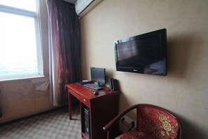 A hotel room with a television mounted on the wall, a desk with a laptop, and a red chair. - Baotai Business Hotel (Shanghai Wusong International Cruise Terminal Songbin Road Subway Station) (Shanghai)