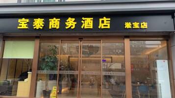 A hotel with a black awning and yellow signage.