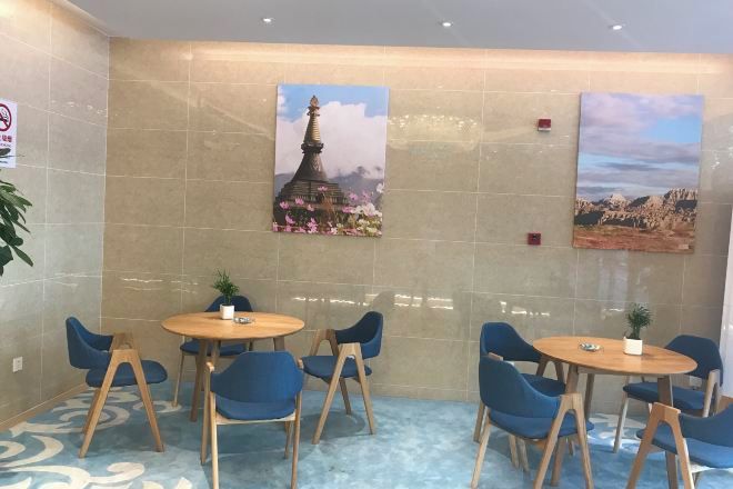 A hotel lobby with a seating area, two paintings on the wall, and a carpeted floor.