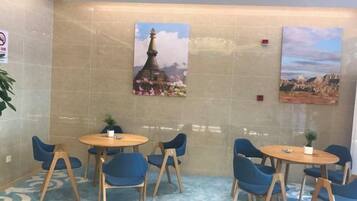 A hotel lobby with a seating area, two paintings on the wall, and a carpeted floor.
