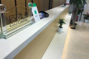 A reception desk with a cash register, a plant, and a small potted plant on the counter. - Baotai Business Hotel (Shanghai Wusong International Cruise Terminal Songbin Road Subway Station) (Shanghai)