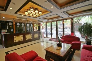 A hotel lobby with a reception desk, red seating, and large windows. - Baotai Business Hotel (Shanghai Wusong International Cruise Terminal Songbin Road Subway Station) (Shanghai)