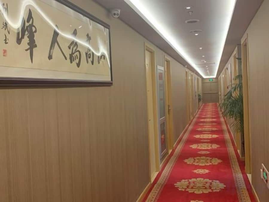 Un pasillo de hotel con alfombra roja, paneles de madera y un letrero con caracteres chinos.