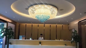 A hotel reception area with a large, circular chandelier, a reception desk, and potted plants. - Baotai Business Hotel (Shanghai Wusong International Cruise Terminal Songbin Road Subway Station) (Shanghai)