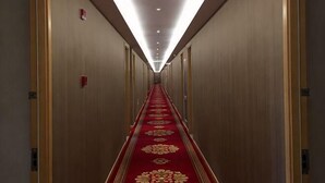 A hotel hallway with a red carpet, wooden walls, and doors on both sides. - Baotai Business Hotel (Shanghai Wusong International Cruise Terminal Songbin Road Subway Station) (Shanghai)
