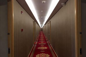 A hotel hallway with a red carpet, wooden walls, and doors on both sides. - Baotai Business Hotel (Shanghai Wusong International Cruise Terminal Songbin Road Subway Station) (Shanghai)