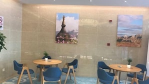 A room with two round tables and blue chairs, a large wall mural, and a tiled floor. - Baotai Business Hotel (Shanghai Wusong International Cruise Terminal Songbin Road Subway Station) (Shanghai)