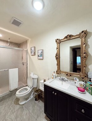 A bathroom with a shower, toilet, vanity, and a large ornate mirror. - The Spanish Hacienda in Rio Grande City (Rio Grande City)