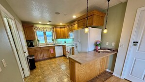A kitchen with wooden cabinets, a central island, and a view of the outdoors through the windows.