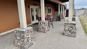 A covered outdoor seating area with stone pillars, a wooden wall, and a 'Welcome' sign.