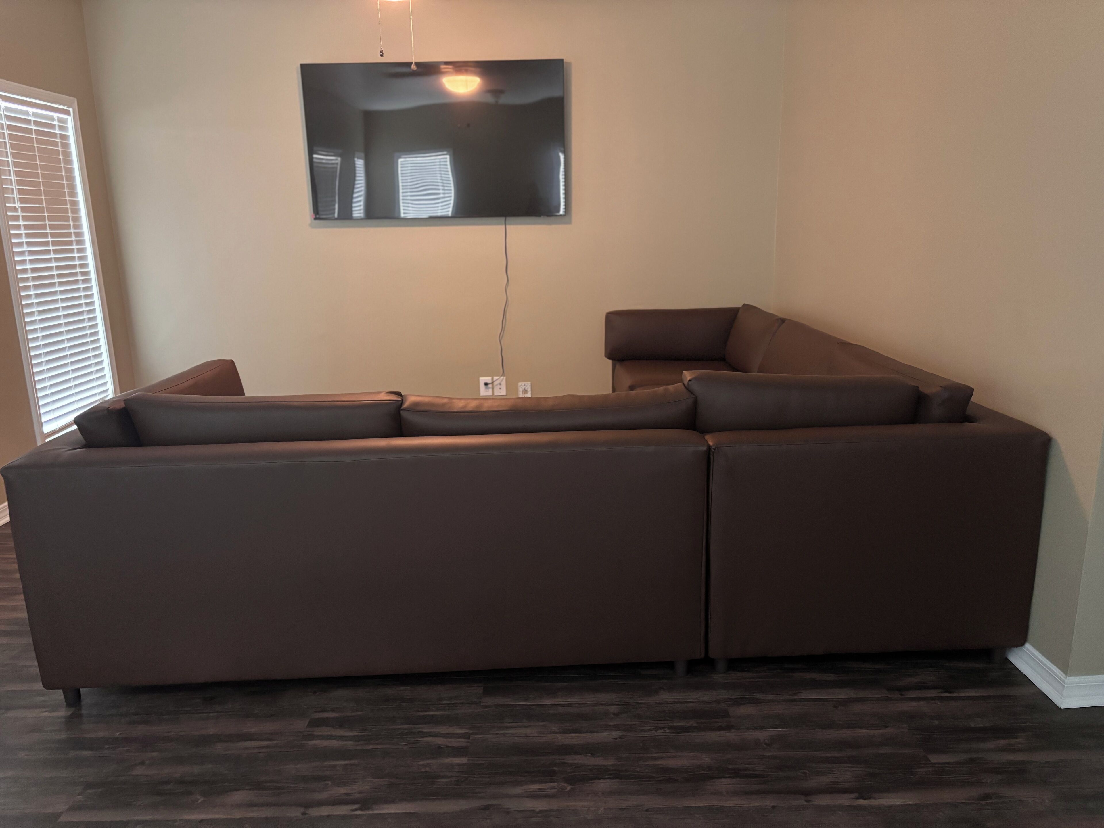A sectional sofa in a living room with a flat-screen TV mounted on the wall.