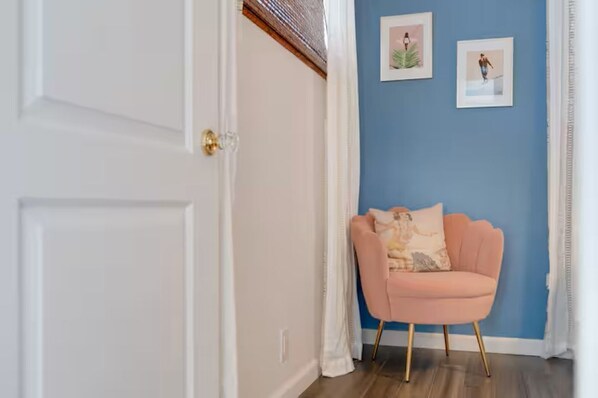 A room with a white door, a blue wall, and a pink chair with a cushion.