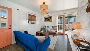 Una sala de estar acogedora con un sofá azul, sillones de mimbre, una mesita y una lámpara.