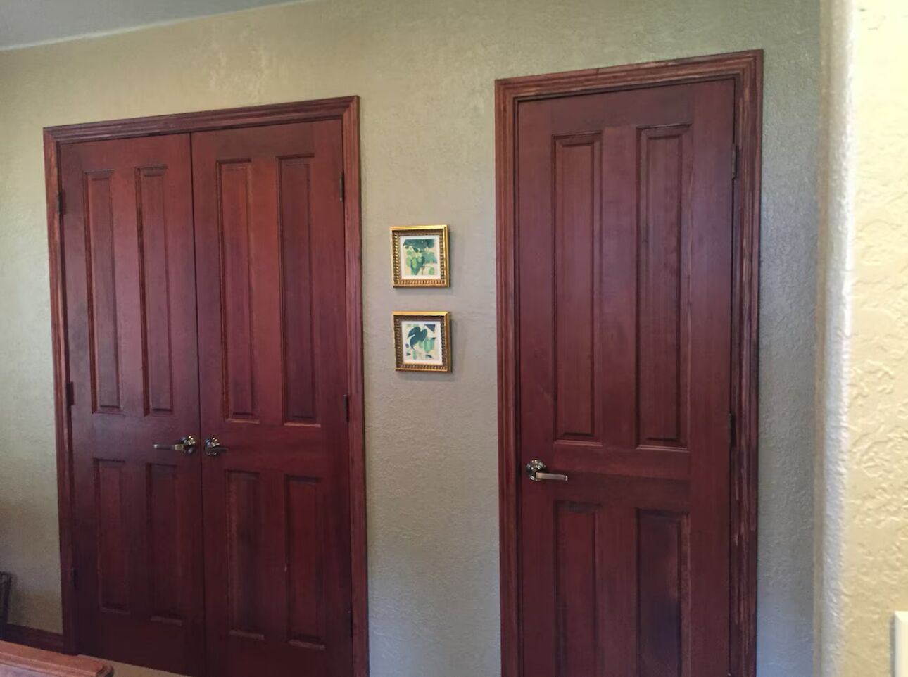 Deux portes en bois, séparées par un petit tableau encadré.
