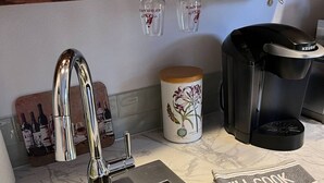 Een keuken met een roestvrijstalen spoelbak, een Keurig koffiezetapparaat, een decoratieve pot en een handdoek met de tekst 'I'll cook'.