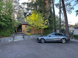Un coche estacionado frente a una casa con un pequeño porche y escalones que suben a ella.