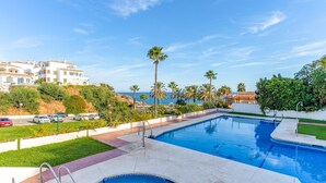 A swimming pool with a view of the sea, surrounded by greenery and a white building. - ‘Frente Al Mar Mijas’ Apartment with Sea Views, Shared Pool and Wi-Fi (Mijas costa)