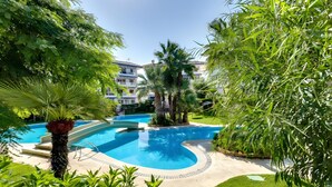 A swimming pool surrounded by lush greenery and a multi-story building with balconies. - Apartment 'Con Piscina' with Shared Pool, Wi-Fi and Air Conditioning (La Mata)