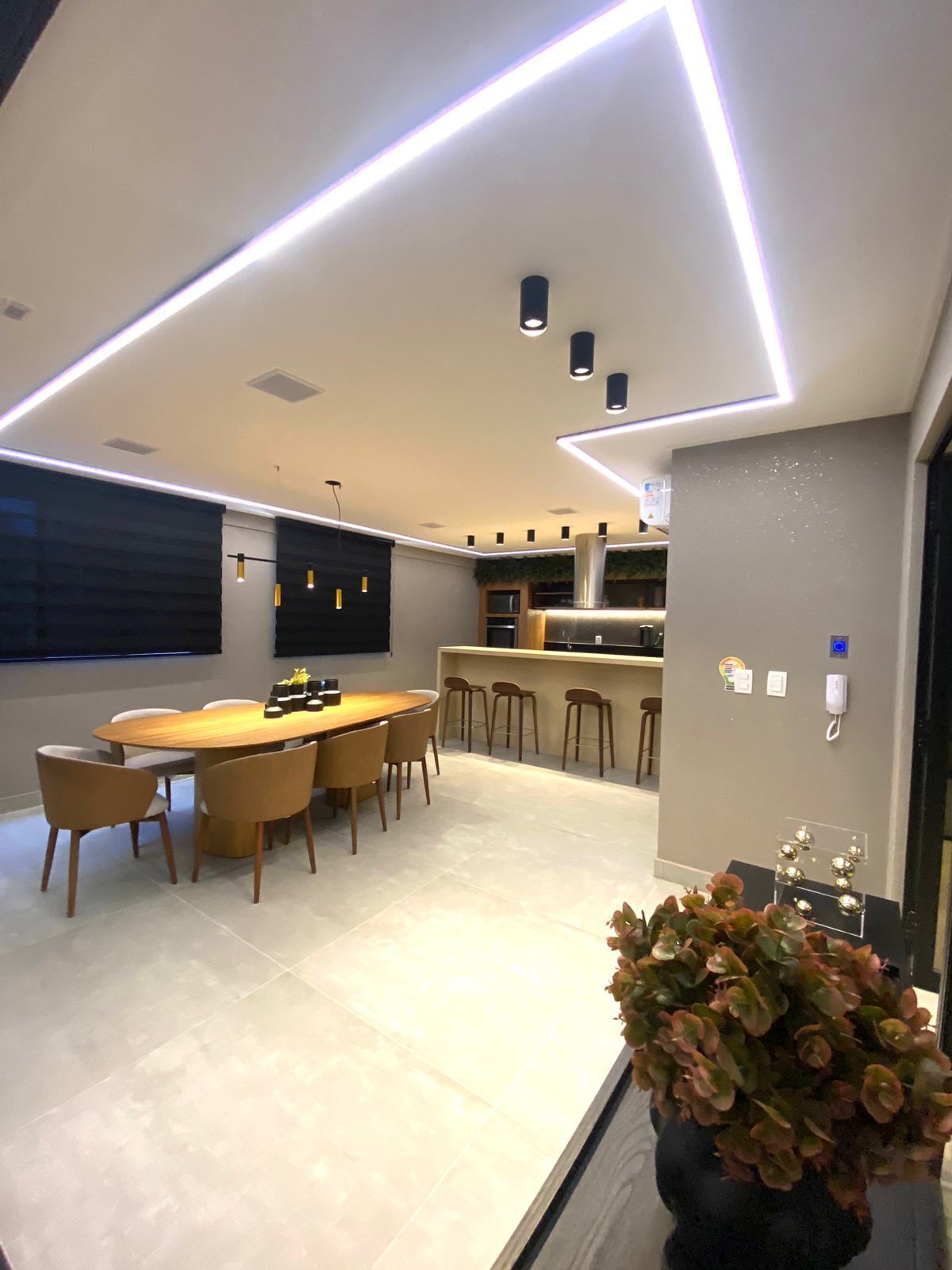 Una cocina moderna con una isla central, iluminación colgante y una zona de comedor con una mesa redonda y sillas.